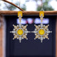 IXXIA Jewelry radiant starburst drop earrings with yellow gemstone, clear stones, gold and silver-toned metals.